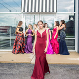 6 girls in front of Sophia's doors all in beautiful prom dresses. Olivia is walking towards the camera in a red sheath prom dress.