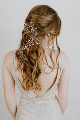 Girl has a low back dress with her hair down and curled.