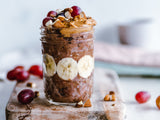 Very yummy looking chocolate smoothie, with banana slices, almonds, peanut butter, and grapes on top.