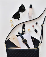 Black purse that has many different items spilling out including: sunglasses, makeup, jewelry, a watch, and an iphone